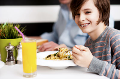 kid with braces smiling while eating lunch